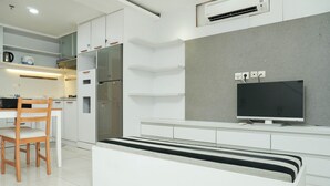 Una cocina moderna con armarios blancos, una estufa empotrada y un televisor de pantalla plana sobre un mueble blanco.