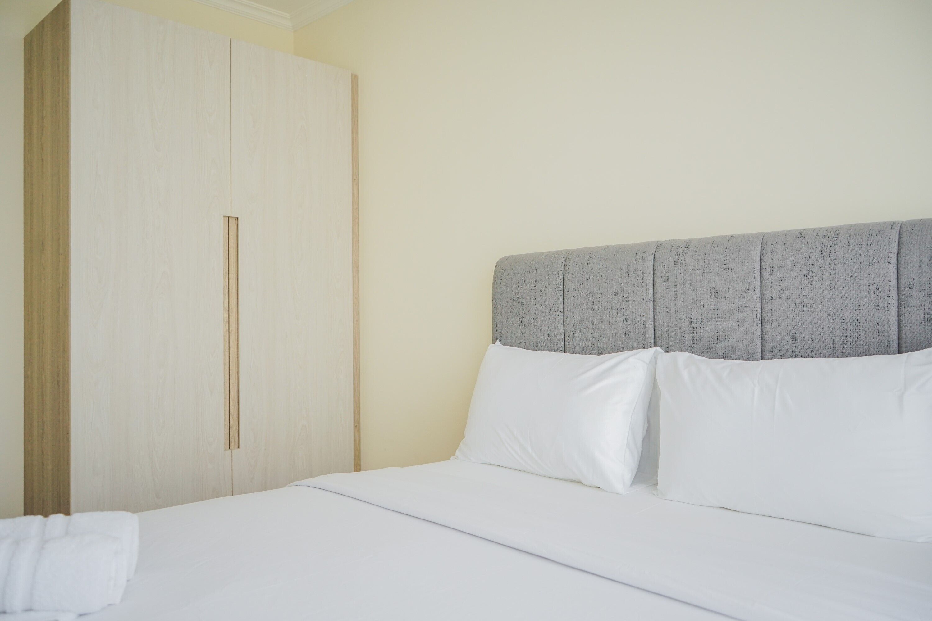 A bedroom with a bed, a wardrobe, and a headboard.