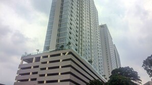 A tall, modern skyscraper with a glass facade and a stepped lower section. - Chic and Cozy 2BR Apartment at Menteng Park (Jakarta)