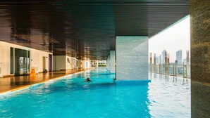 Una piscina interior amb vista a l'horitzó urbà, un paviment de fusta i un disseny de sostre modern.