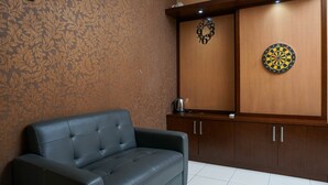 A room with a patterned wallpaper, a black leather sofa, wooden cabinets, and a dartboard. - Comfy and Homey 2BR at Mediterania Marina Ancol Apartment (Jakarta)