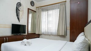 A neatly made bed with rolled towels, a television on a wooden dresser, and a large mirror above the dresser. - Comfy and Homey 2BR at Mediterania Marina Ancol Apartment (Jakarta)