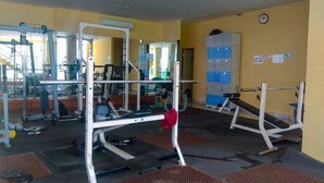 A gym with weightlifting equipment, mirrors, and lockers.