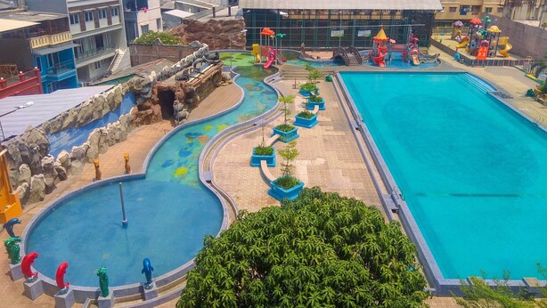 A swimming pool with a water slide and a rock formation.