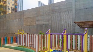 A playground with colorful equipment and a concrete wall in the background.