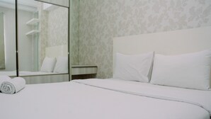 A hotel room with a neatly made bed, a large mirror, and a patterned wallpaper.