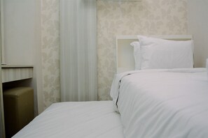 A neatly made bed with white linens in a hotel room with floral wallpaper and a closed window.