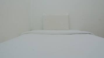 A small, plain room with a single bed and a pillow.