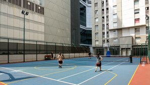 An indoor tennis court with a blue playing surface and yellow boundary lines.