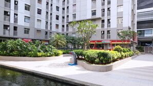 A modern building with multiple floors, balconies, and a landscaped courtyard with a water feature.
