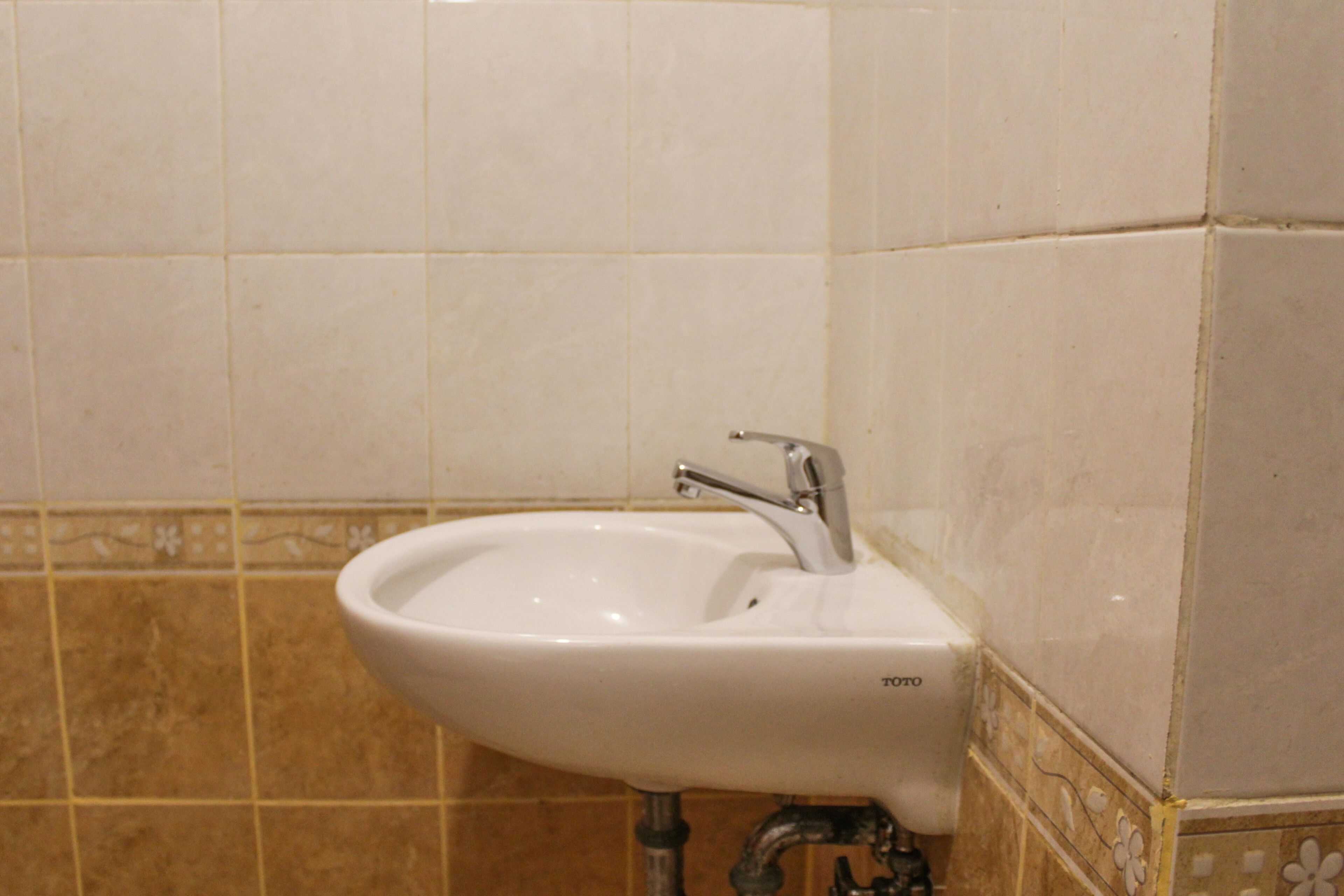 A bathroom with a white sink, a faucet, and tiled walls.