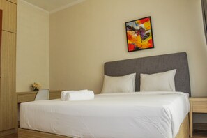 A hotel room with a large bed, a gray headboard, and a colorful abstract painting on the wall. - Best Deal 2BR Apartment at Grand Palace Kemayoran (Jakarta)
