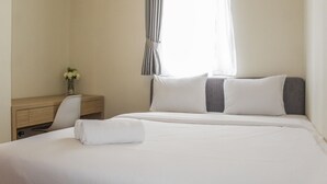 Siisti hotellihuone, jossa on huolitellusti pedattu sänky, työpöytä tuolilla ja ikkuna, jossa on verhot.