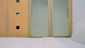 Une chambre à coucher avec un lit, une armoire en bois et des portes en verre dépoli.