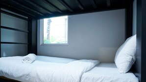 Ein Einzelbett mit weißer Bettwäsche in einem Zimmer mit Fenster.