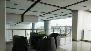 A modern interior with a balcony, glass railings, and a city view. - Beautiful Studio at Cosmo Terrace Apartment (Jakarta)