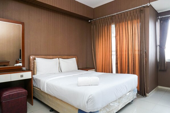 Una habitación de hotel con una cama grande, un escritorio de madera, un espejo y una silla roja.