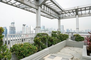 Una terraza en la azotea con vistas a un horizonte urbano, con edificios modernos y una grúa de construcción.
