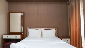 A hotel room with a bed, a wooden nightstand, a mirror, and a window with curtains. - Beautiful Studio at Cosmo Terrace Apartment (Jakarta)