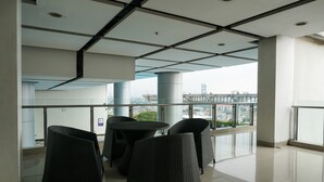 Ein moderner Innenraum mit Glastrennwand, schwarzem Rattanmöbel und Blick auf die Stadt.