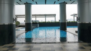 Ein Dachpool mit Blick auf die Skyline der Stadt, umgeben von hohen Säulen und einem überdachten Gang.