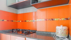 Une cuisine avec des meubles de couleur orange, une cuisinière à gaz et un four à micro-ondes.