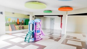 Un hall d’entrée spacieux avec un espace de jeux coloré, une fresque murale et un sol à motifs.