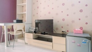Une chambre équipée d’un téléviseur posé sur un meuble, d’un petit réfrigérateur et d’un bureau avec une chaise.