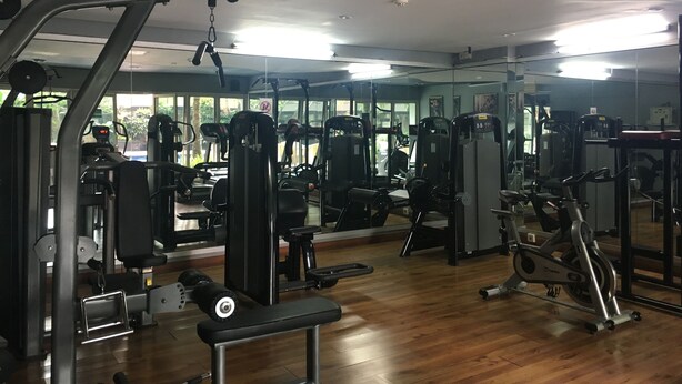 A gym with various exercise machines, a bench, and a mirrored wall. - Spacious & Comfy 2BR at Galeri Ciumbuleuit Apartment (Bandung)