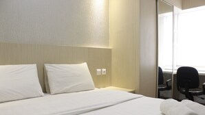 A hotel room with a neatly made bed, a bedside table, a chair, and a large mirror.