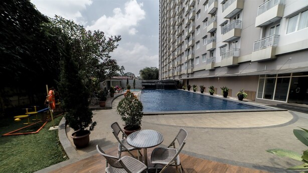 A courtyard with a swimming pool, outdoor seating, and a tall residential building. - Charming Studio Room at Galeri Ciumbuleuit 2 Apartment (Bandung)