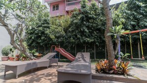 A patio area with lounge chairs, a slide, and potted plants. - Charming Studio Room at Galeri Ciumbuleuit 2 Apartment (Bandung)