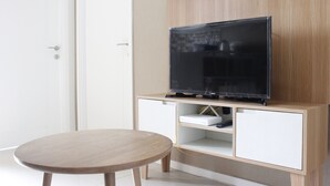 Una habitación moderna con un armario de madera, un televisor encima y una mesa redonda.