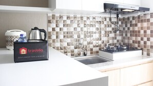Una cocina moderna con encimera blanca, estufa a gas, pileta y salpicadero con baldosas geométricas. Se observan una cafetera de marca y una bolsa de viaje sobre la encimera.