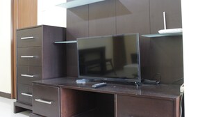 Ein dunkles Holz-Entertainment-Center mit einem Flachbildfernseher, einer Fernbedienung und einem weißen elektronischen Gerät darauf.