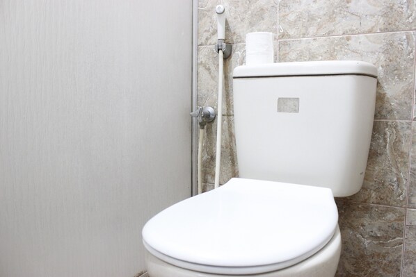 A white toilet with a marble-tiled wall behind it.