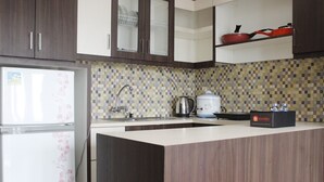 A modern kitchen with a refrigerator, a sink, and a coffee maker. - Modern Studio Room at Tamansari La Grande Apartment (Bandung)