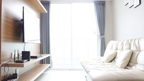 Une chambre moderne avec un lit, un téléviseur fixé au mur et un bureau équipé d’appareils électroniques.