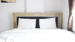 A neatly made bed with white bedding and a wooden headboard. - Comfortable & Gorgeous 2BR at Gateway Pasteur Apartment (Cimahi)