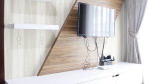 Una habitación moderna con un televisor montado en una pared de madera, una consola blanca y un enchufe.