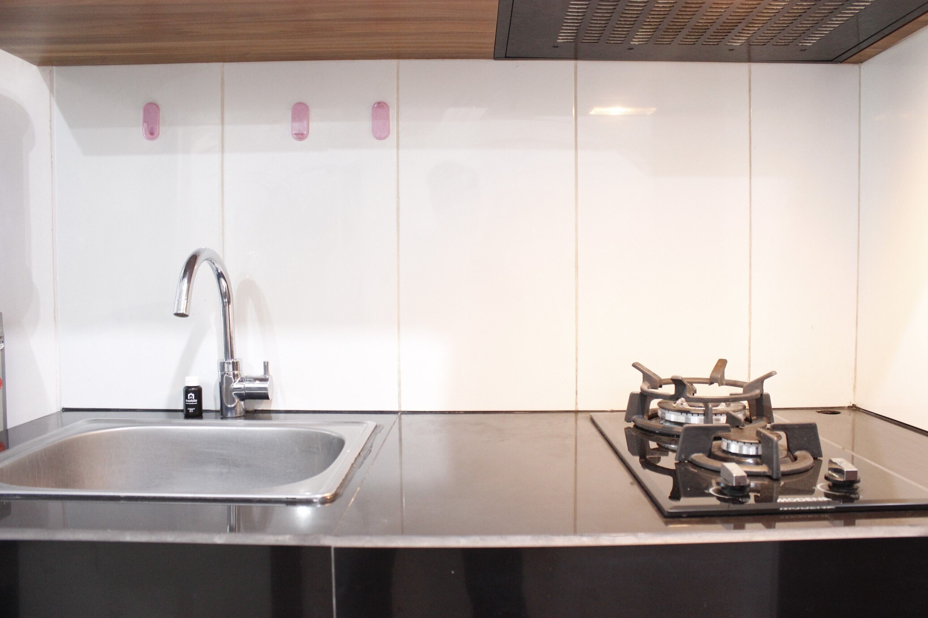 A modern kitchen with a stainless steel sink, a gas stove, and white cabinets.