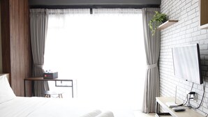 A hotel room with a bed, a desk with a computer, and a TV mounted on the wall. - Artistic & Scenic Studio at Gateway Pasteur near Cimahi (Cimahi)
