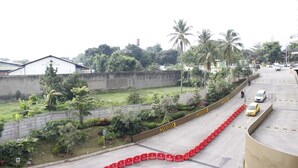 A road with red barriers, a white building, and palm trees. - Artistic & Scenic Studio at Gateway Pasteur near Cimahi (Cimahi)