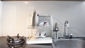 A kitchen with a stainless steel sink, a stove, and a dish drying rack. - Artistic & Scenic Studio at Gateway Pasteur near Cimahi (Cimahi)