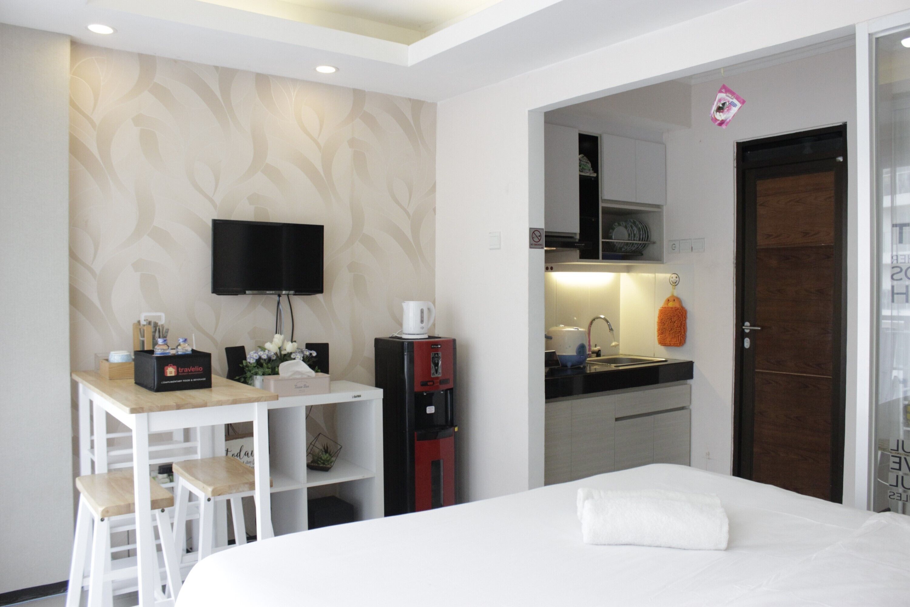 Une chambre d’hôtel comprenant un lit, un bureau avec un téléviseur à écran plat, une machine à café et une petite kitchenette.