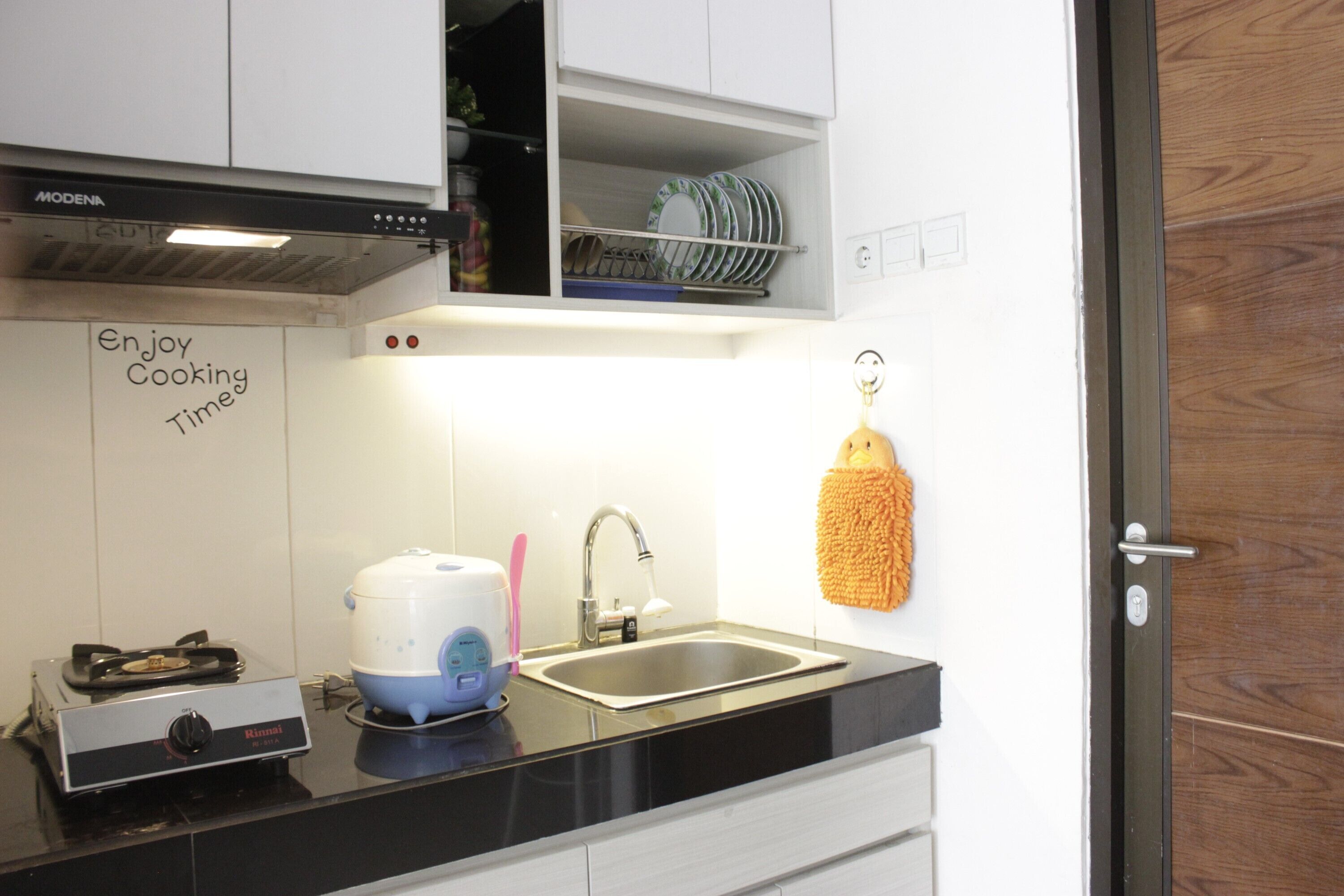 A kitchen with a stove, a sink, and a sign that says "Enjoy Cooking Time".