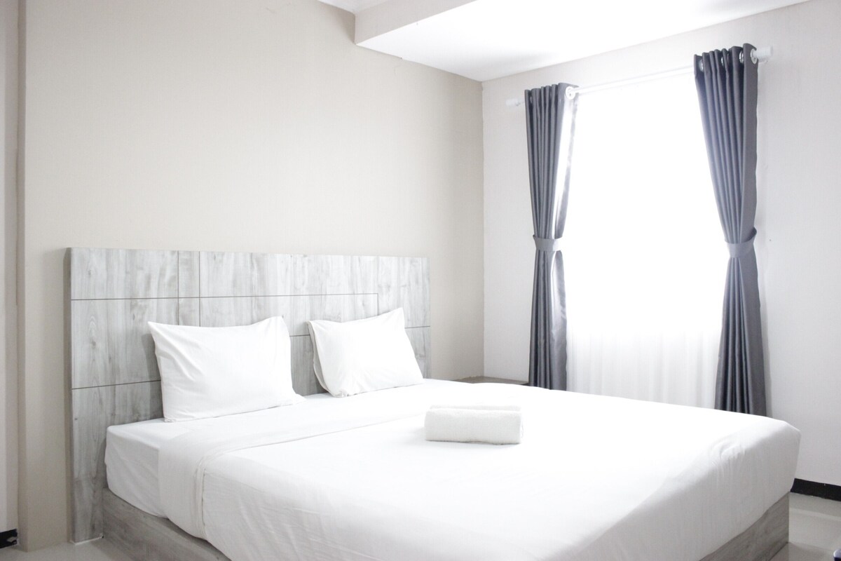 Una habitación de hotel moderna con una cama grande, ropa de cama blanca y un cabecero de madera.