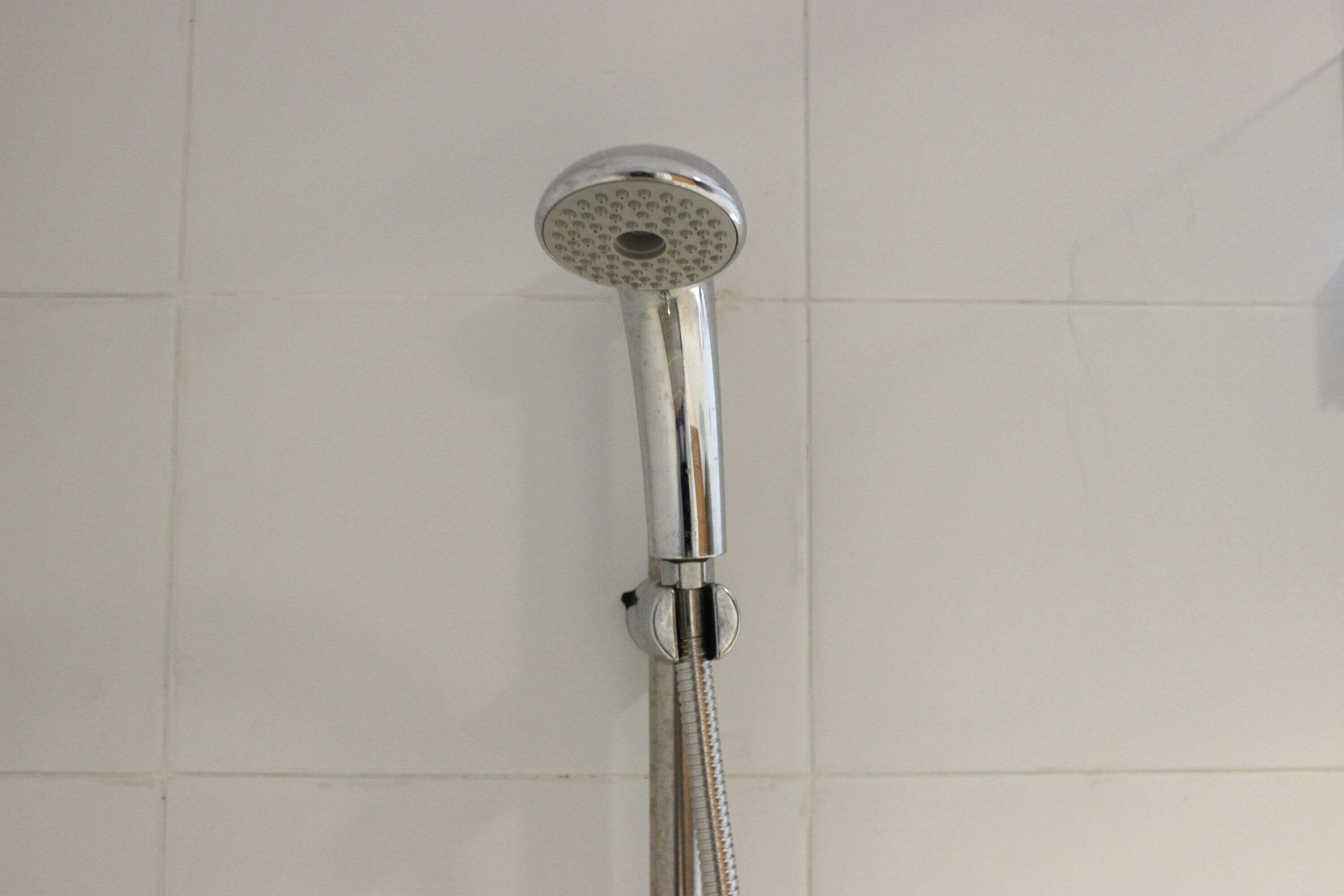 Un cabezal de ducha instalado en una pared con azulejos.