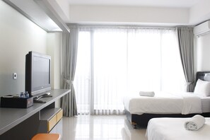 Une chambre d’hôtel avec un lit, un bureau avec une télévision et une fenêtre avec des rideaux.