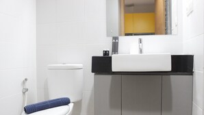 Un baño con inodoro blanco, lavamanos con encimera negra y armarios grises.